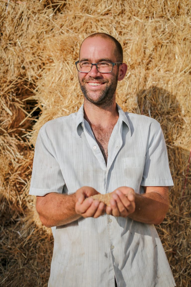 Photo de Matthieu Fillacier avec une poignée de grains de blé dans le creux de ses mains. Découvrez sa démarche en tant que paysan boulanger.